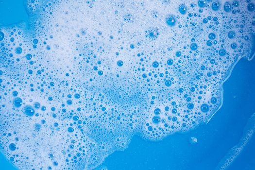 Detergent foam bubble on blue background. Top view