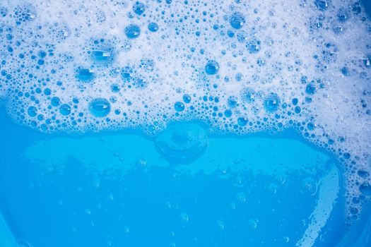 Detergent foam bubble on blue background. Top view
