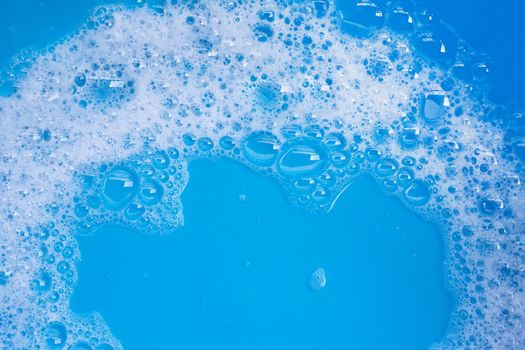 Detergent foam bubble on blue background. Top view