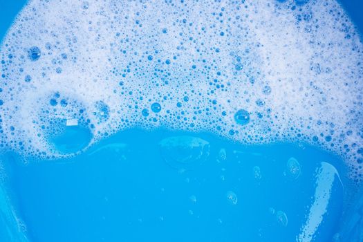 Detergent foam bubble on blue background. Top view