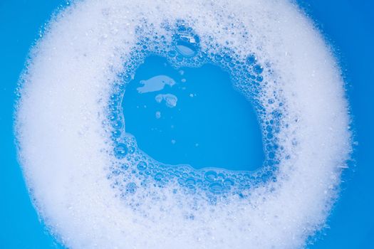 Detergent foam bubble on blue background. Top view