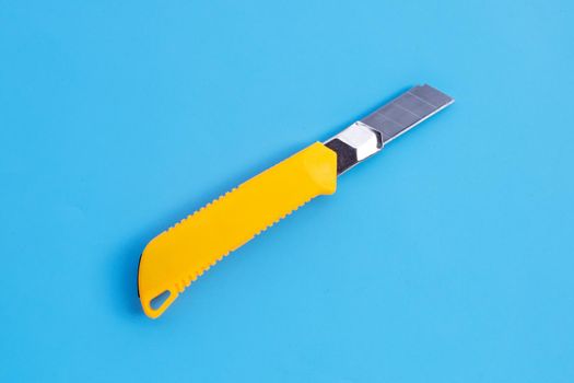 Stationery knife on blue background.