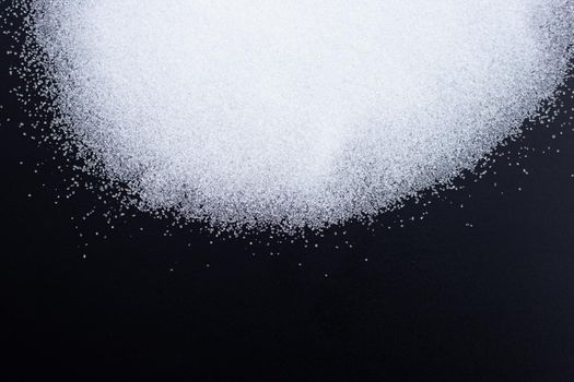 White granulated sugar on dark background. Copy space