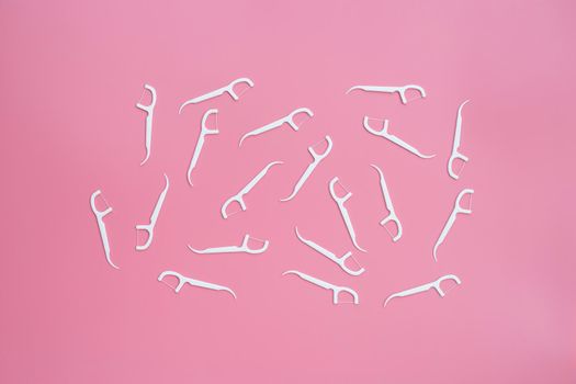 White floss toothpicks on pink background. Copy space