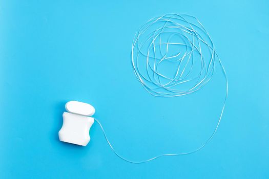 Dental floss on blue background. Copy space