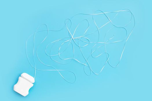 Dental floss on blue background. Copy space