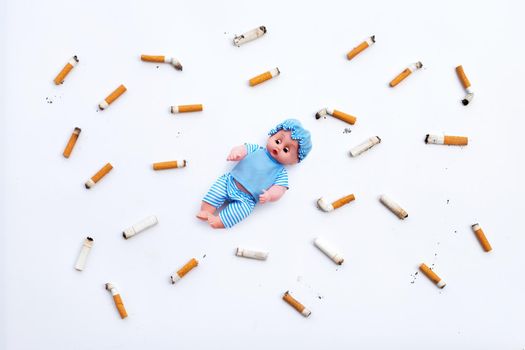 Baby doll with  cigarette butts and ashes on white background.