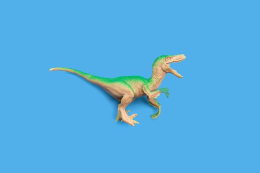 Plastic dinosaur toy on blue background. Top view