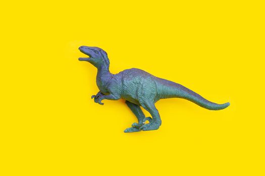 Plastic dinosaur toy on yellow background. 