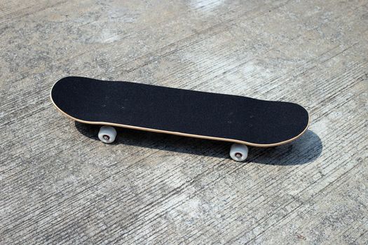 Black skateboard on cement ground.