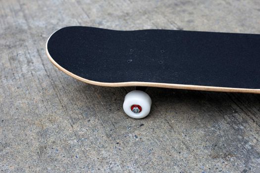 Black skateboard on cement ground.