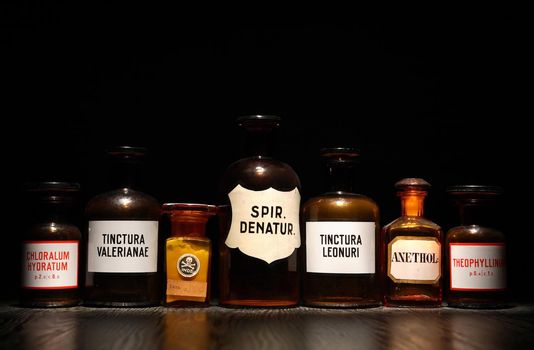 Few old bottles with medicines in a row on dark background