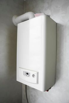 White modern home gas boiler mounted on a grey wall on a kitchen. Water heater. Water heating, ecology