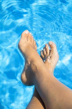 Slim legs of young woman in swimming pool. Summer time