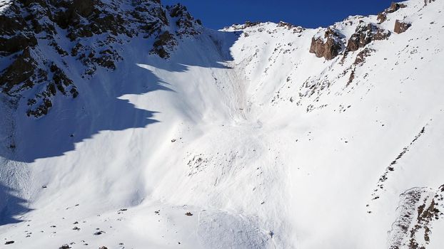 There was an avalanche in the mountains. Top view from the drone. Steep slopes and large rocks. A dangerous place. There were several avalanches. Snow-capped peaks of the Trans-Ili Alatau. Almaty