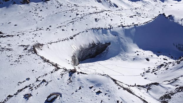 A huge wall of ice. Bogdanovich Glacier in the mountains of Almaty. The wind blows the snow away from the high frozen wave. Unusual shape and color of the ice. Moraine lake in winter in the mountains