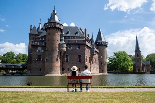 Castle de Haar Utrecht, couple men and woman mid age European and Asian visit De Haar Castle in Dutch Kasteel de Haar is located in Utrecht Netherlands during Spring with flowers in the garden