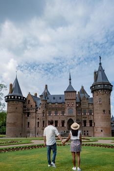 Castle de Haar Utrecht, couple men and woman mid age European and Asian visit De Haar Castle in Dutch Kasteel de Haar is located in Utrecht Netherlands during Spring with flowers in the garden