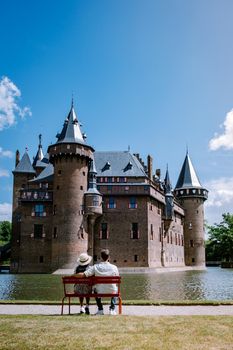 Castle de Haar Utrecht, couple men and woman mid age European and Asian visit De Haar Castle in Dutch Kasteel de Haar is located in Utrecht Netherlands during Spring with flowers in the garden