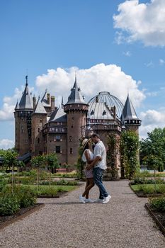 Castle de Haar Utrecht, couple men and woman mid age European and Asian visit De Haar Castle in Dutch Kasteel de Haar is located in Utrecht Netherlands during Spring with flowers in the garden