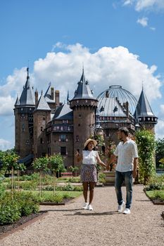 Castle de Haar Utrecht, couple men and woman mid age European and Asian visit De Haar Castle in Dutch Kasteel de Haar is located in Utrecht Netherlands during Spring with flowers in the garden