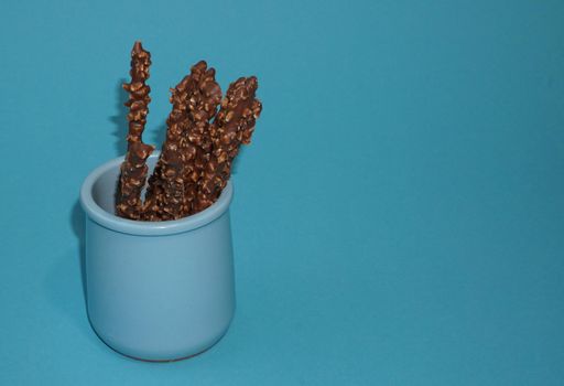 Chocolate crispy sticks with hazelnut sprinkles on a blue background.