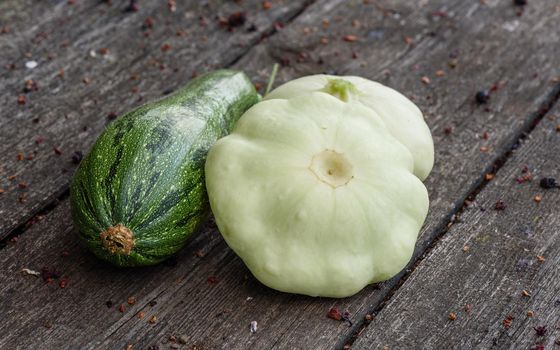 Zucchini with two pattypan squash harvested from the vegetable garden beds lie on the wooden table