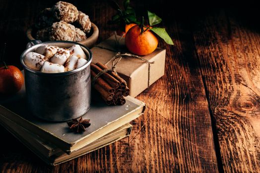 Rustic metal mug of hot chocolate with marshmallows. Tangerines, spices and gingerbread.