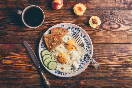 Breakfast toast with fried eggs with vegetables on plate and cup of coffee with fruits over dark wooden background, top view. Clean eating concept.