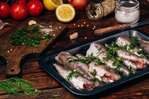 Hake carcasses on baking sheet with vegetables and spices