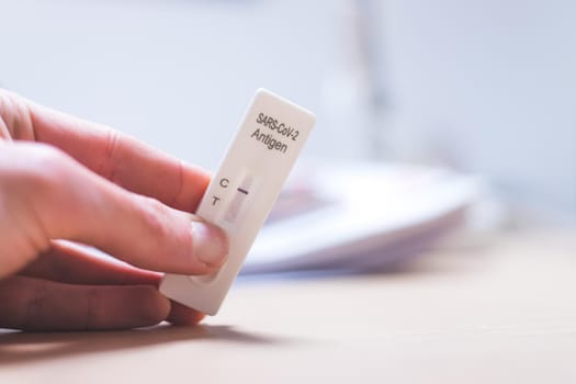 Close up of fingers holding express antigen covid test, negative result