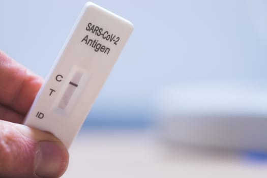 Close up of fingers holding express antigen covid test, negative result
