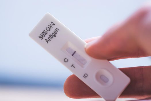 Close up of fingers holding express antigen covid test, negative result