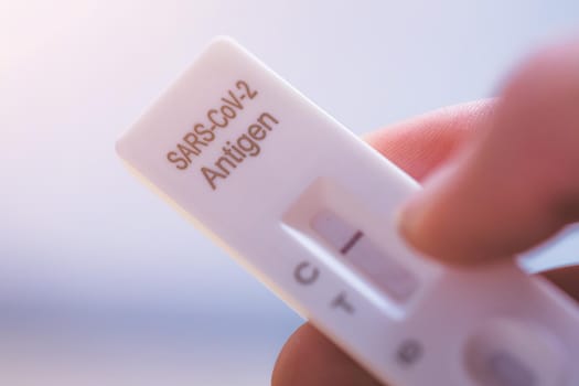 Close up of fingers holding express antigen covid test, negative result