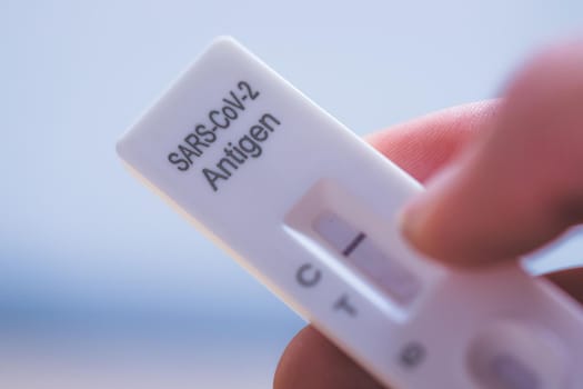Close up of fingers holding express antigen covid test, negative result
