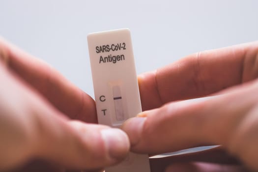 Close up of fingers holding express antigen covid test, negative result