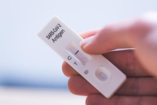 Close up of fingers holding express antigen covid test, negative result