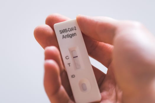 Close up of fingers holding express antigen covid test, negative result