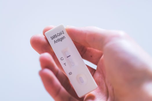 Close up of fingers holding express antigen covid test, negative result