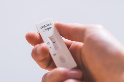 Close up of fingers holding express antigen covid test, negative result