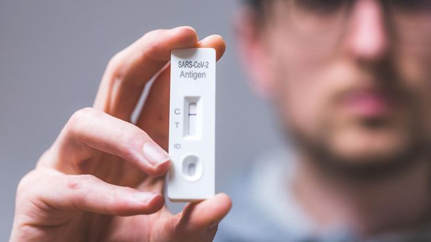 Close up of young man holding express antigen covid test, negative result