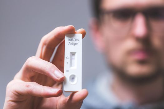 Close up of young man holding express antigen covid test, negative result