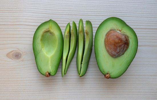 Slices of ripe avocado lie on a light cutting board.
