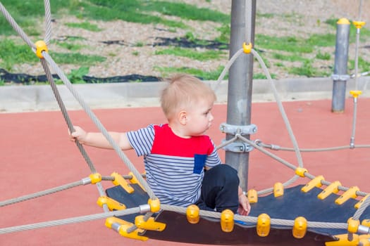 A little boy enthusiastically plays on the playground. Success, creative ideas and sports concepts. Children's playground. Games. 