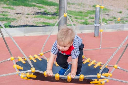 A little boy enthusiastically plays on the playground. Success, creative ideas and sports concepts. Children's playground. Games. 