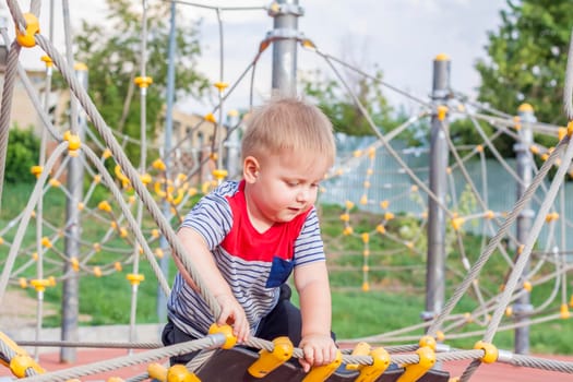 A little boy enthusiastically plays on the playground. Success, creative ideas and sports concepts. Children's playground. Games. 