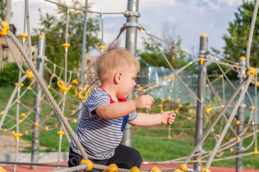 A little boy enthusiastically plays on the playground. Success, creative ideas and sports concepts. Children's playground. Games. 