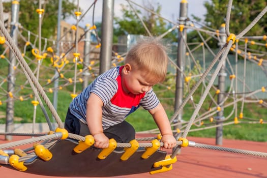 A little boy enthusiastically plays on the playground. Success, creative ideas and sports concepts. Children's playground. Games.