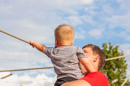 A happy father hugs his little son tightly and with great love. Games with my father. The father hugs the boy. 