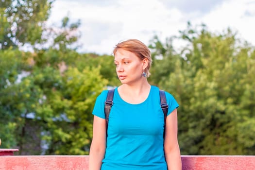 Portrait of a young girl. A girl in a blue T-shirt is standing on the street. The expression on his face. Portrait